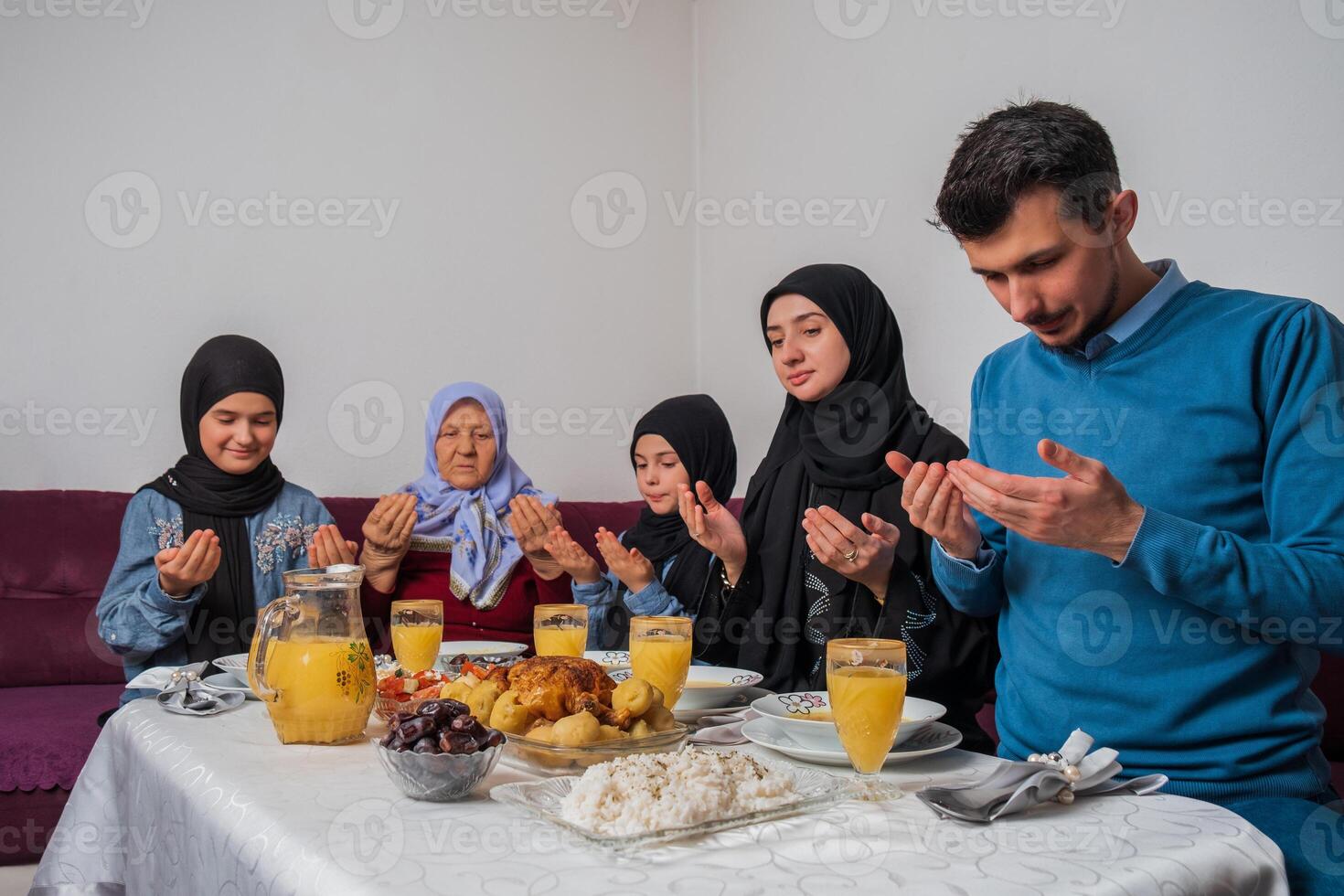 Muslim family making iftar dua to break fasting during Ramadan happy parents having dinner with their children and grandmother at dining table at home. photo
