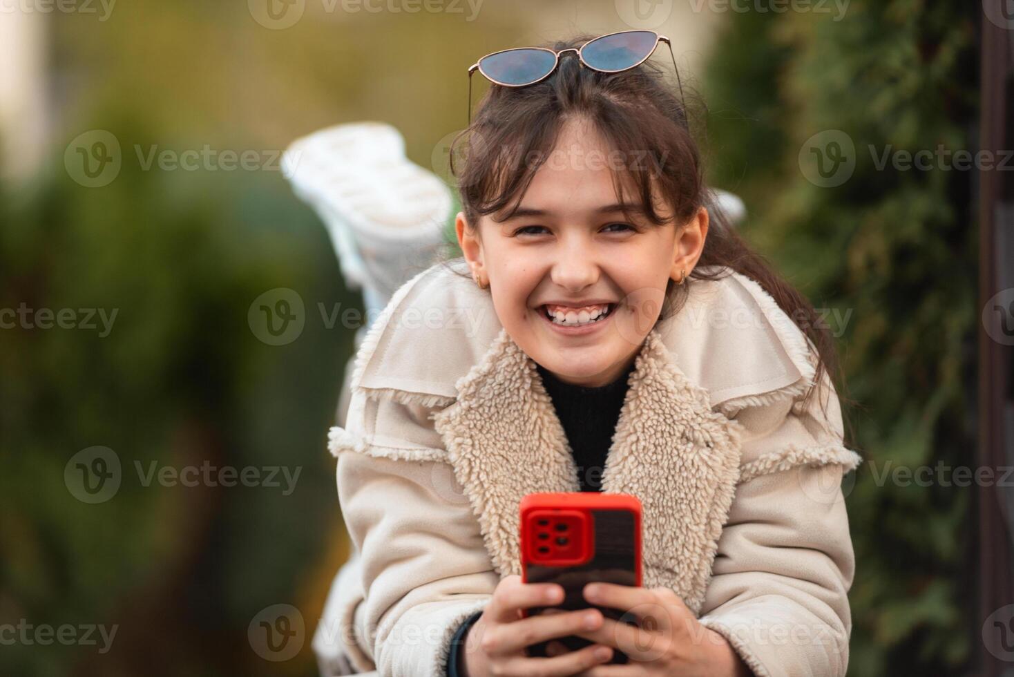 A happy teenage girl using a phone outside. photo