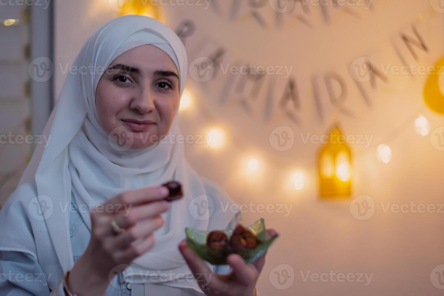A happy Muslim woman eating dates for iftar to break fast during the holy month Ramadan concept of passing sharing food. photo