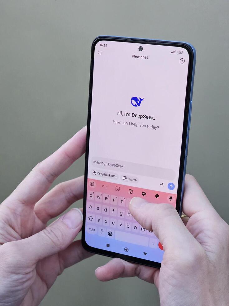 Travnik, Bosnia and Herzegovina, 02.08.2025. Close up of Asian female hands using DeepSeek app chat on phone to solve a reasoning problem on an isolated background, real photo. photo