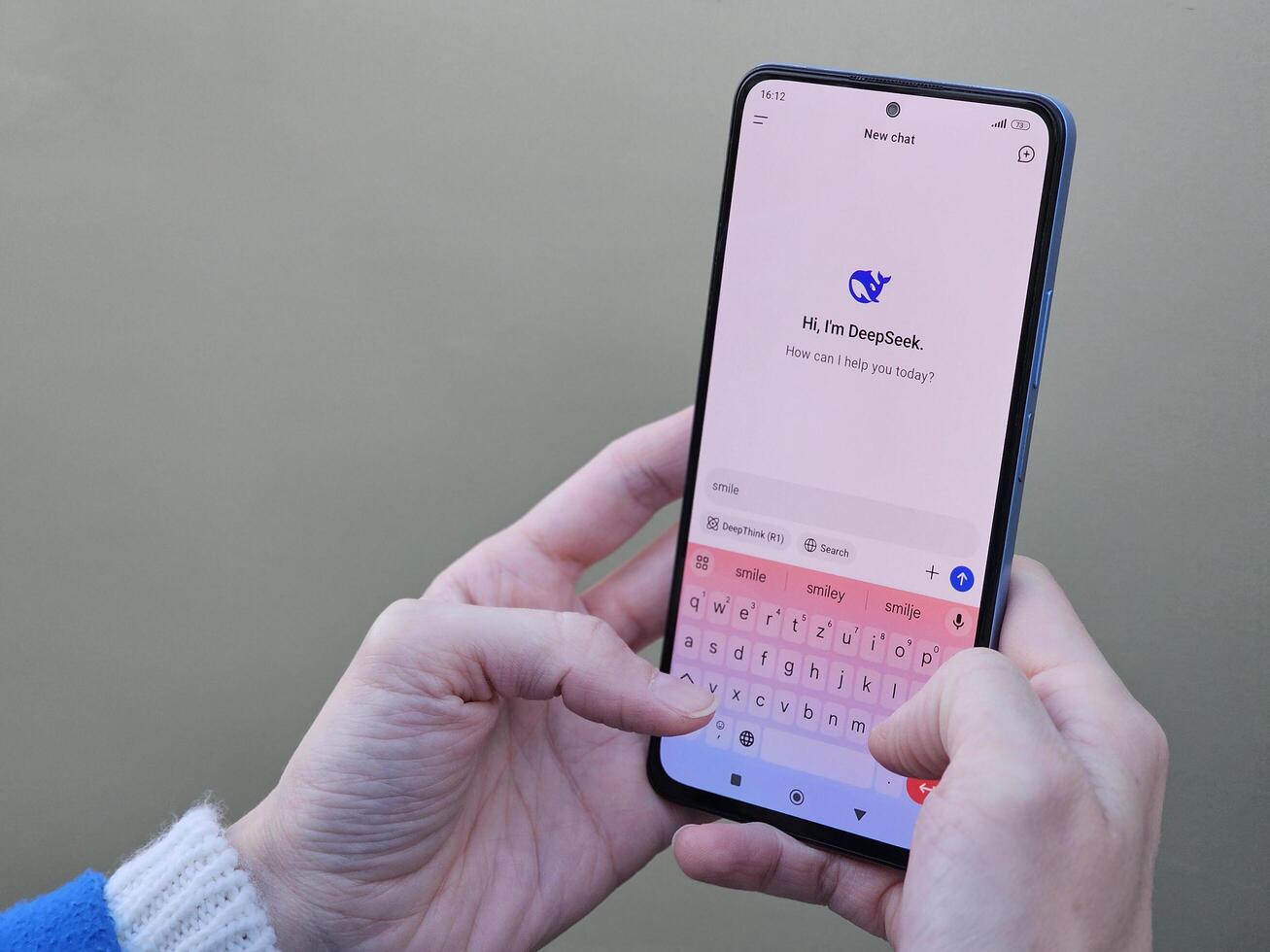 Travnik, Bosnia and Herzegovina, 02.08.2025. Close up of Asian female hands using DeepSeek app chat on phone to solve a reasoning problem on an isolated background, real photo. photo