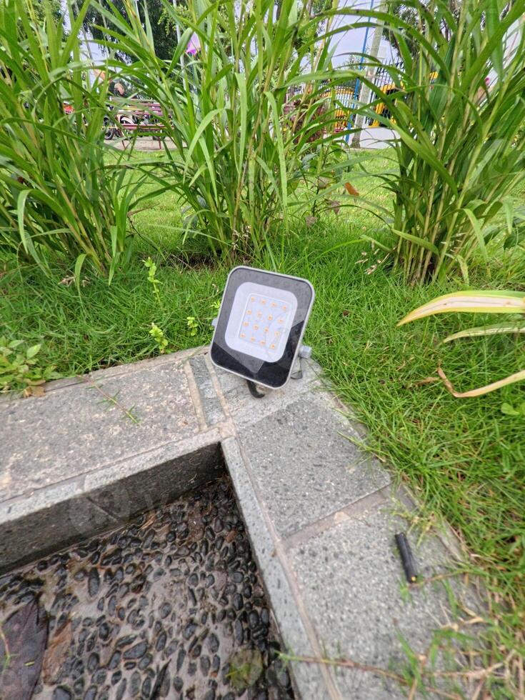 Outdoor Light Fixture Amidst Green Plants and Stone photo