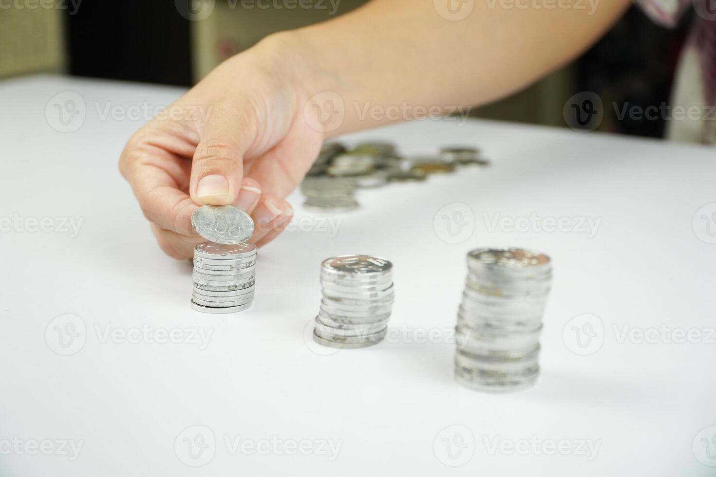 A person putting coins into a stack of coins photo