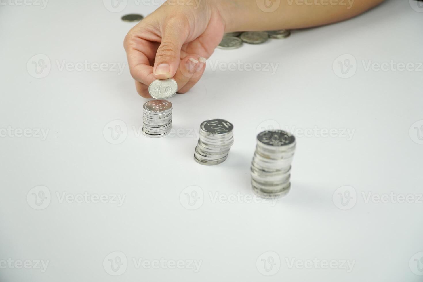A person putting coins into a stack of coins photo