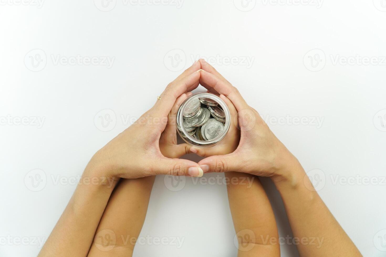 Two hands holding a small coin in the shape of a heart photo