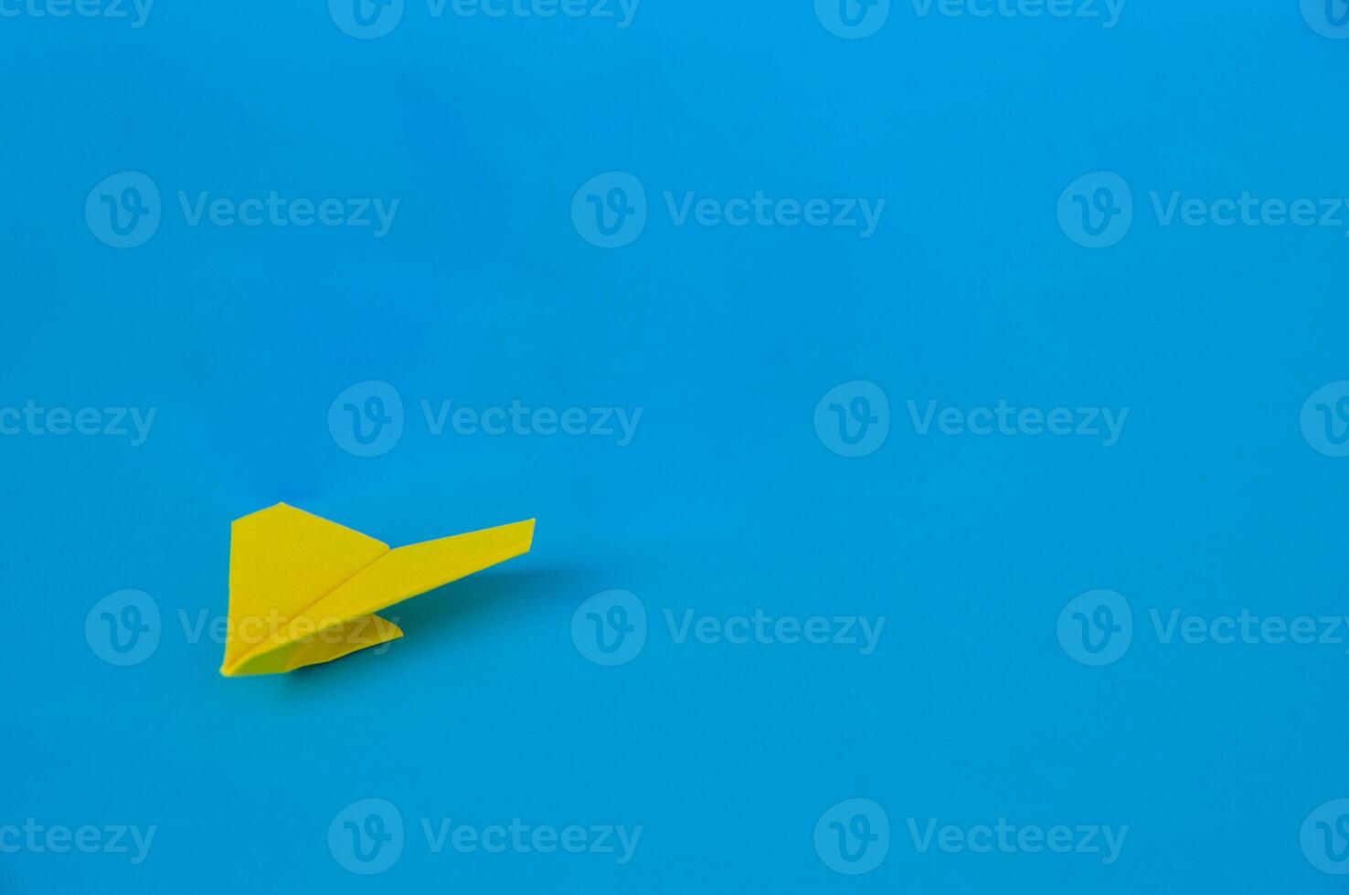 Side view of yellow paper airplane on blue background with customizable space for text. Business and Leadership skills concept photo