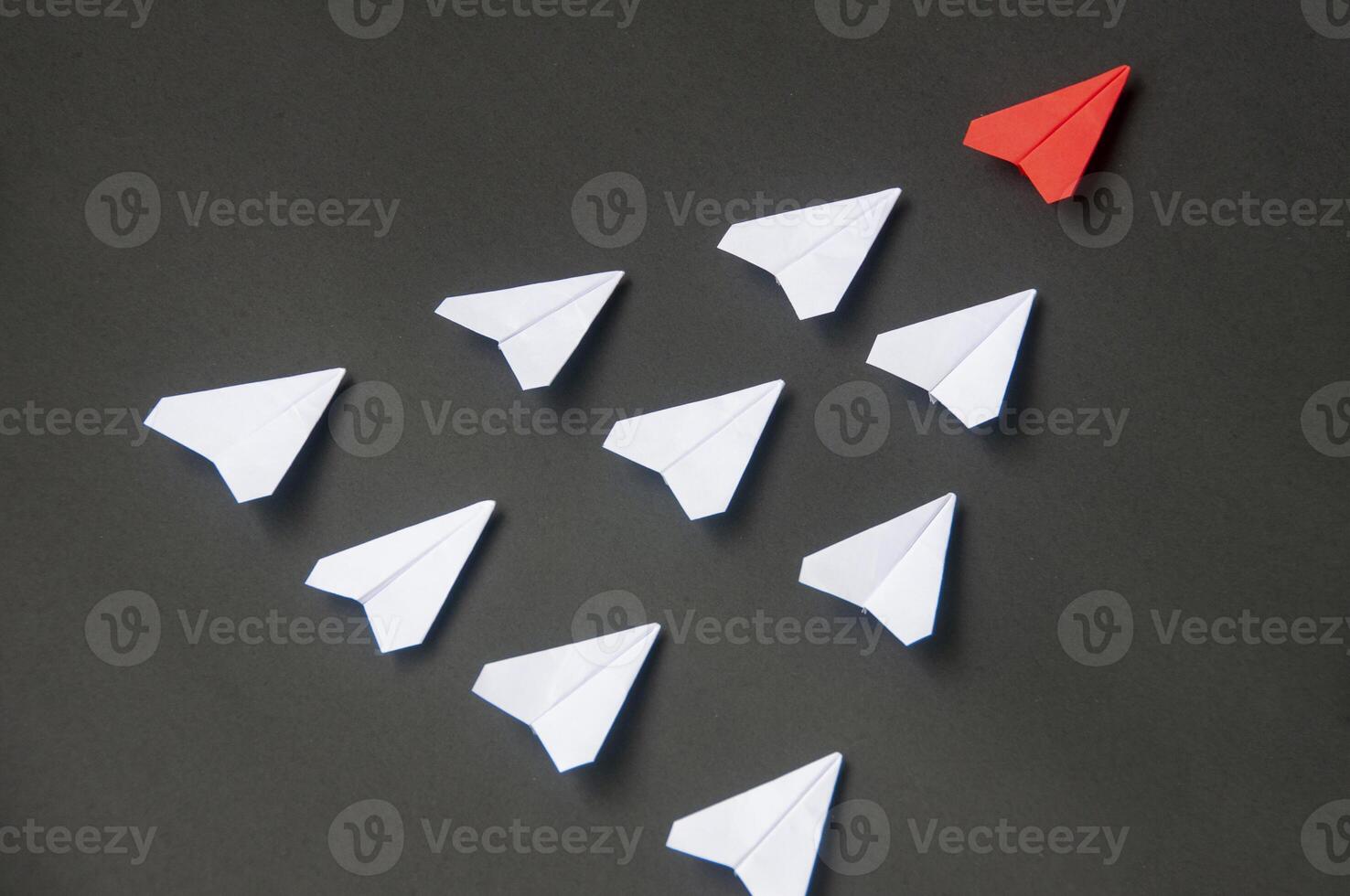 Top view of red paper airplane origami leading white airplanes on blue dark background. Leadership skills concept photo