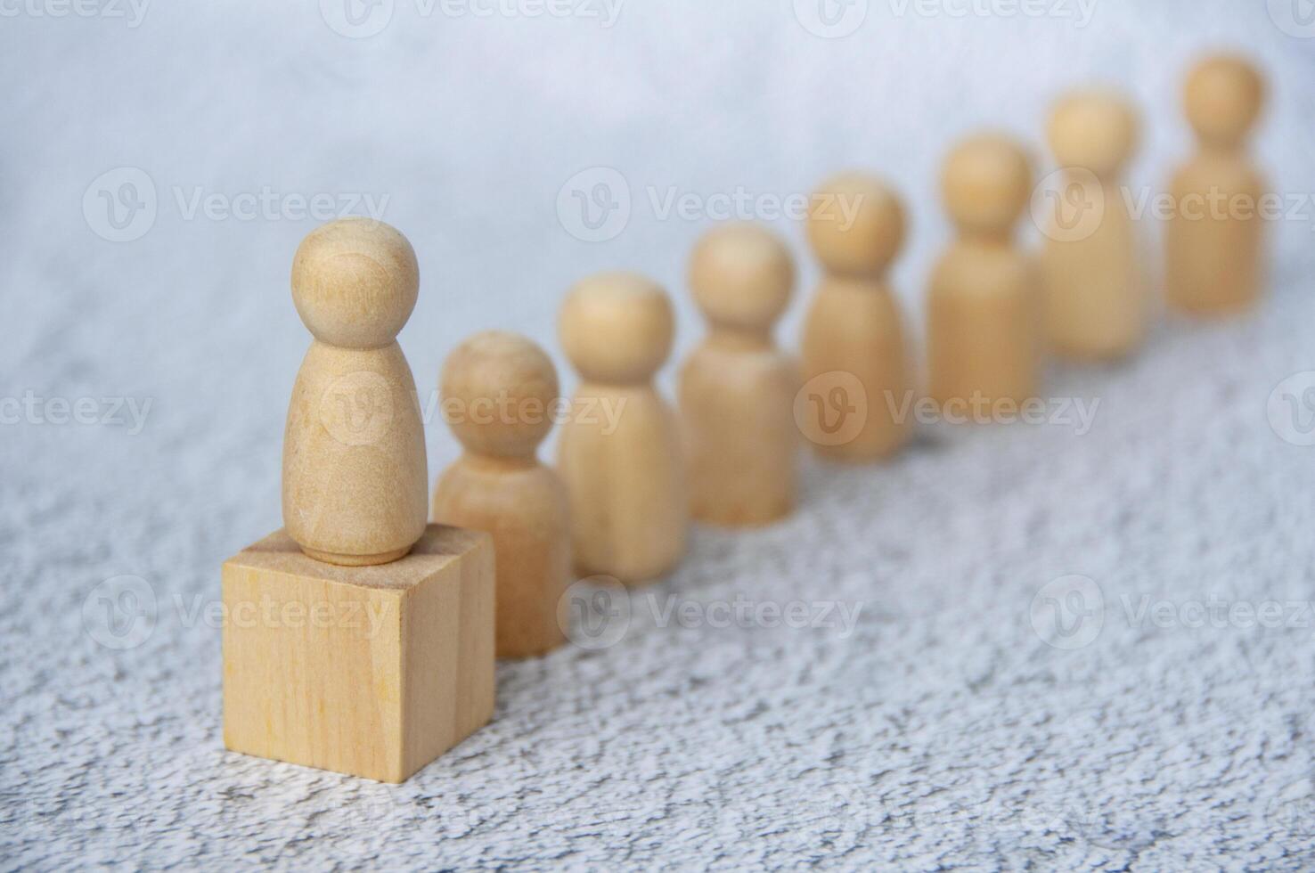 A wooden figure doll leading other figure dolls with customizable space for text. Empowerment and leadership concept photo