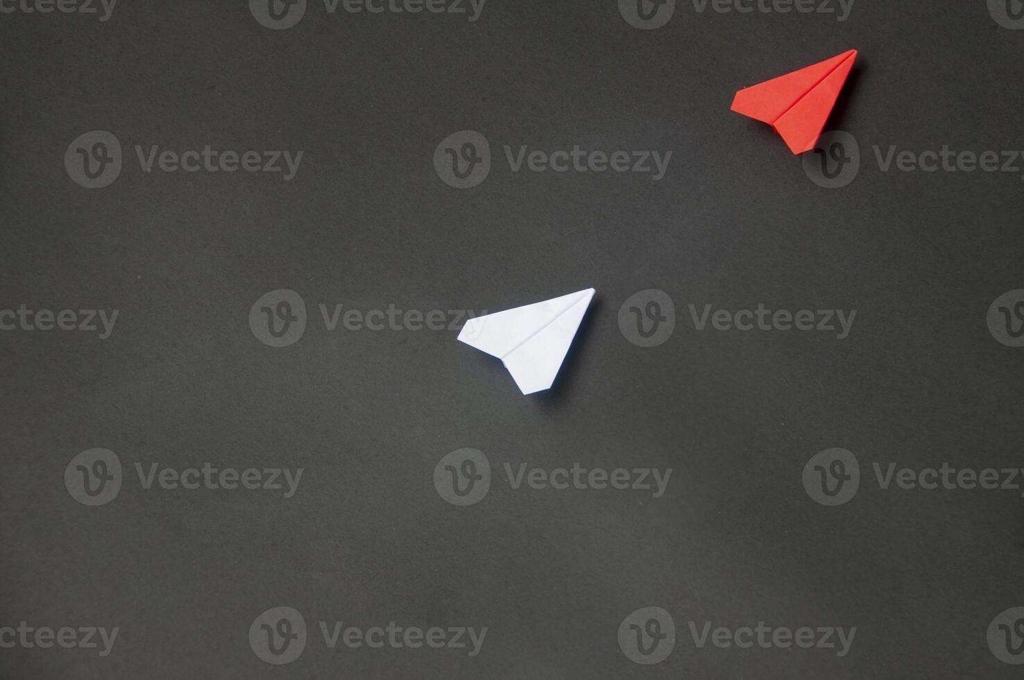Top view of red paper airplane origami leading white airplane on blue dark background. Leadership skills concept photo