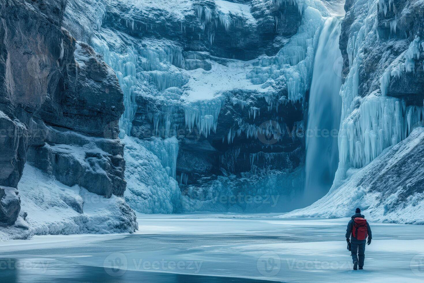 A man standing in front of a waterfall in the snow photo
