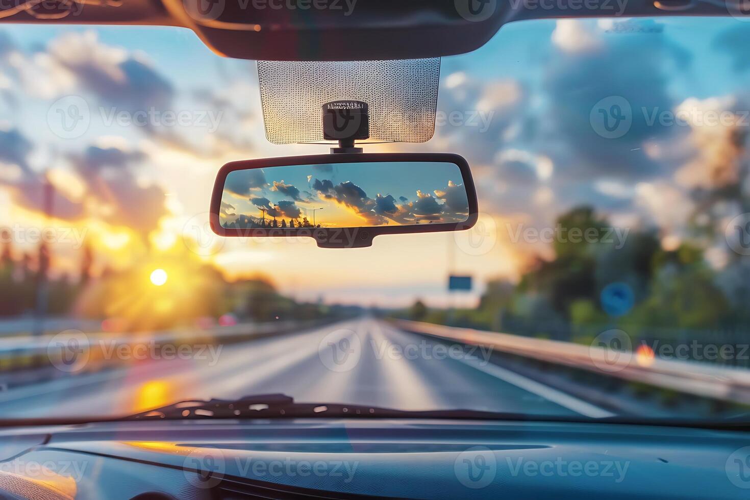 A car's rear view mirror is seen through the windshield photo