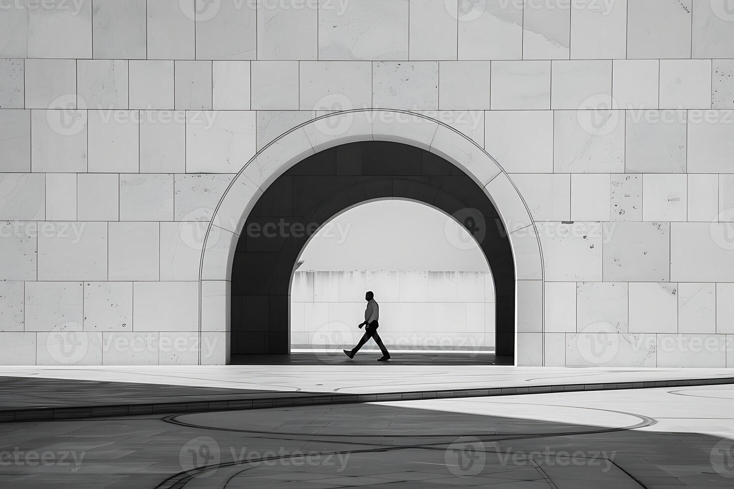 A man walking through an archway in a white building photo