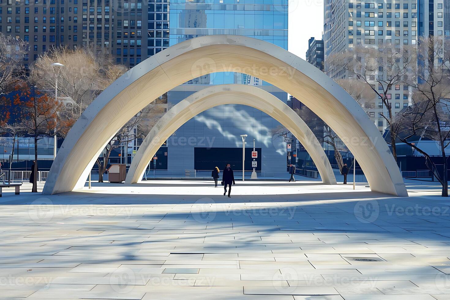 A person walking in a city with a large arch photo