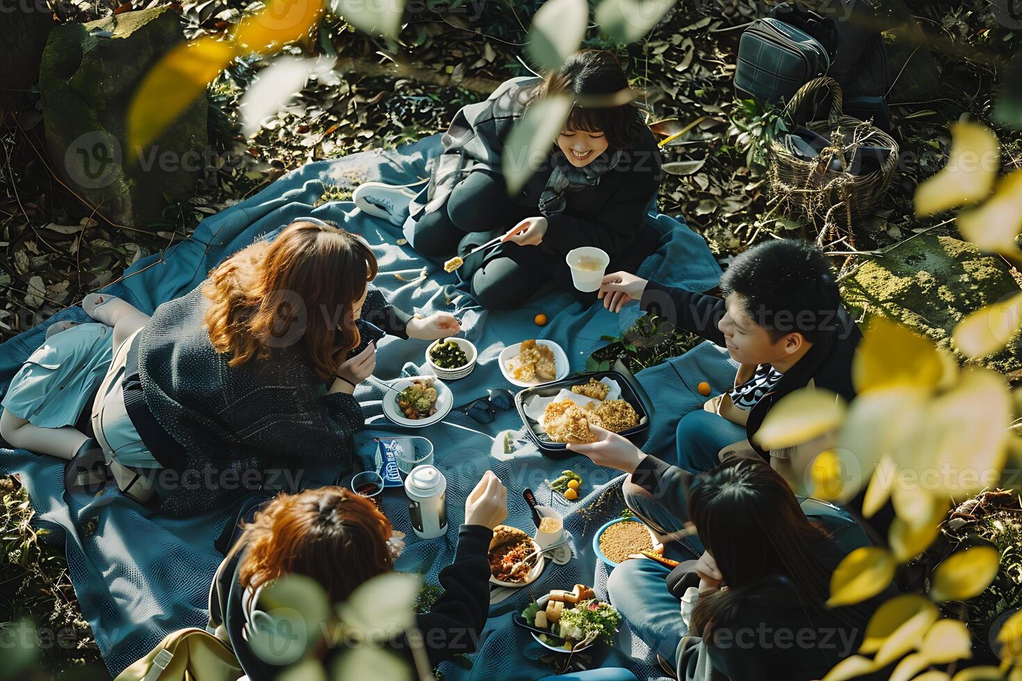 A group of people eating food on a blanket photo