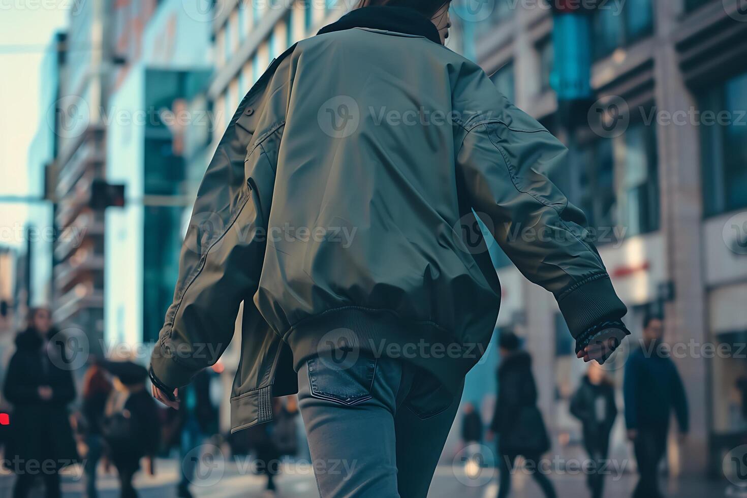A man in a green jacket walking down a street photo