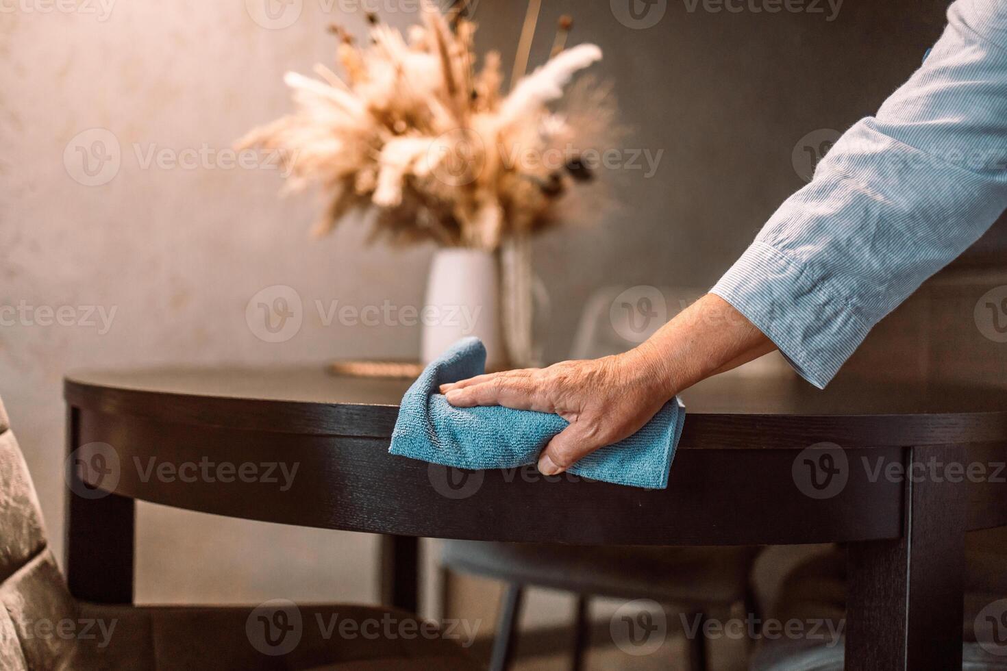 Close up woman cleaning wooden table using disinfectant blue towel. Prevent infection of Covid-19 virus, contamination of germs or bacteria, wipe or cleaning to eliminate, outbreak of Coronavirus. photo