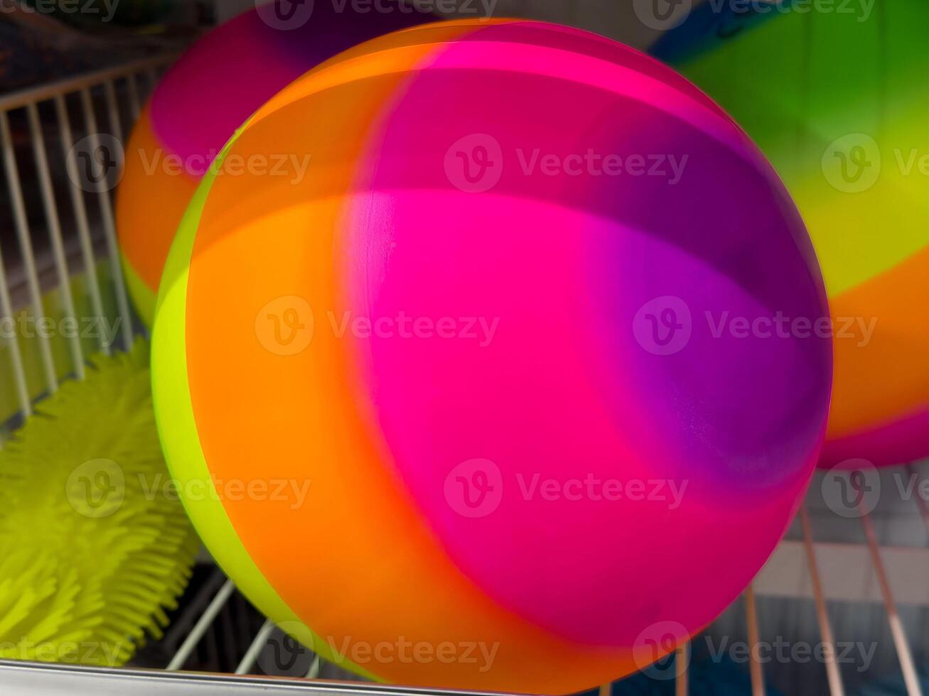 Vibrant multicolored beach ball with neon green toy in sunlit storage photo