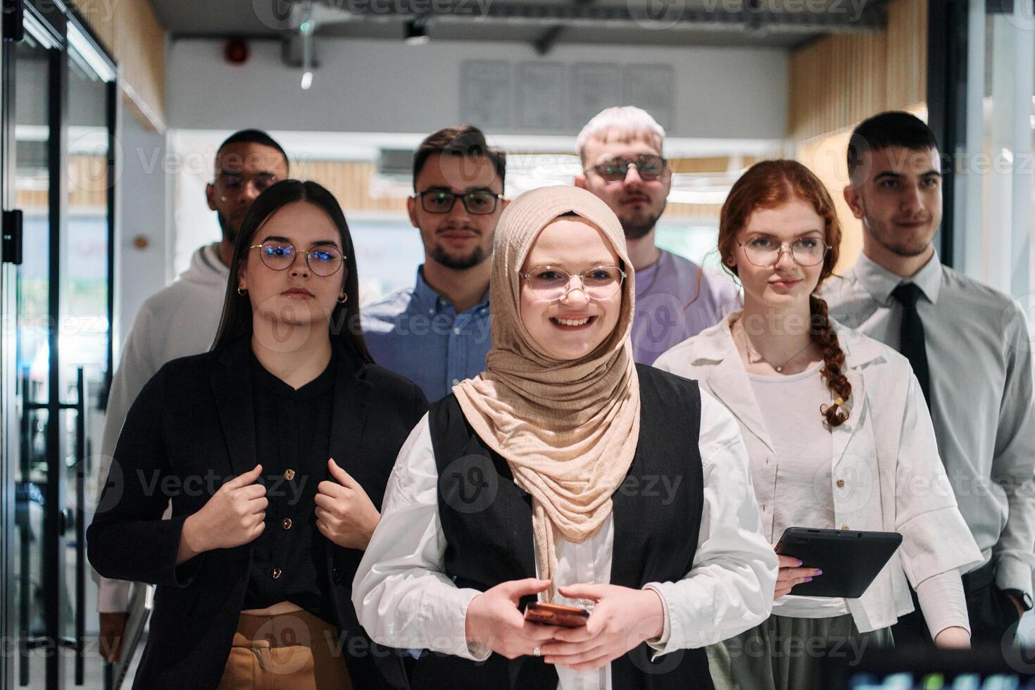 A group of business professionals standing together, taking a well-deserved break from their busy workday, showcasing camaraderie, teamwork, and a moment of relaxation in their dynamic workplace photo