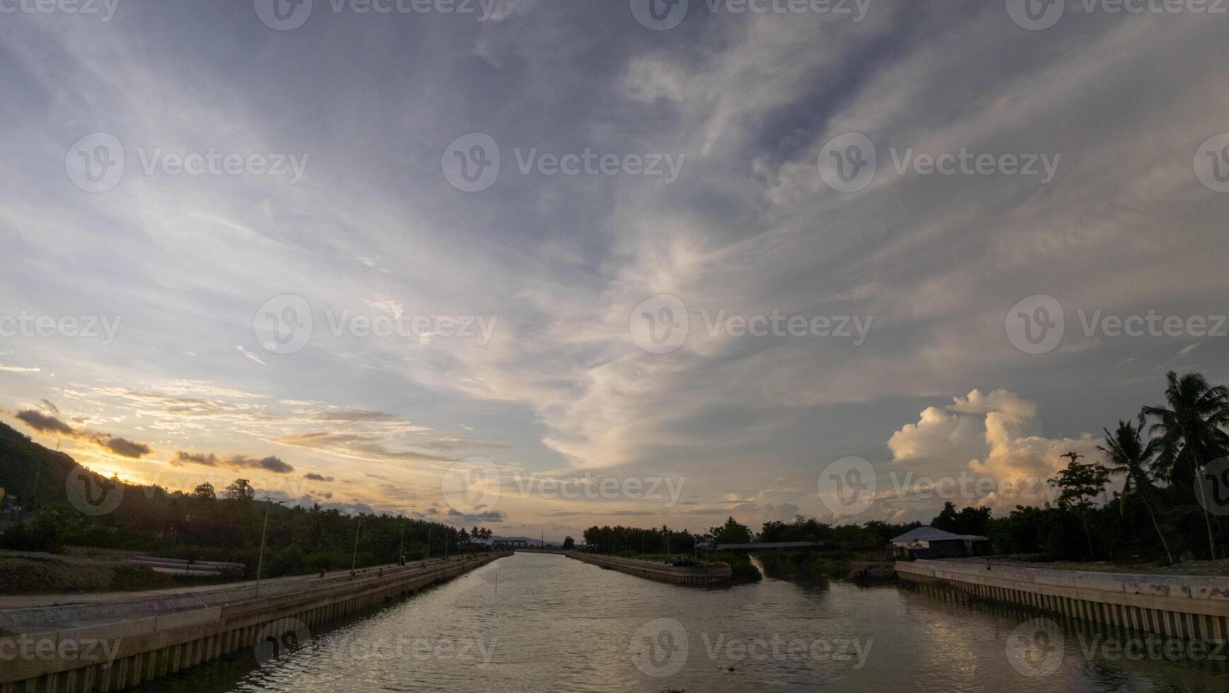 A canal with a bridge and a sunset in the background photo