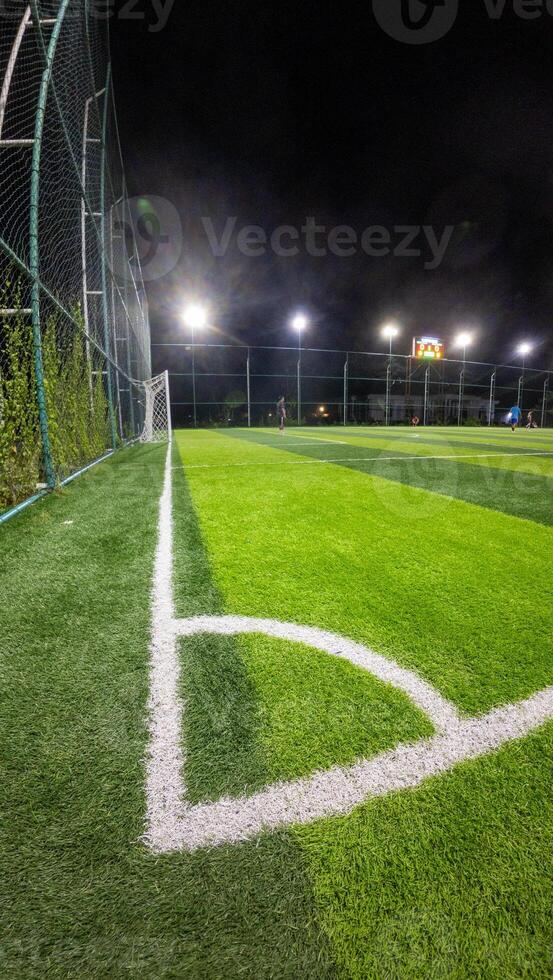 Soccer field with green grass and white line at night in Indonesia photo