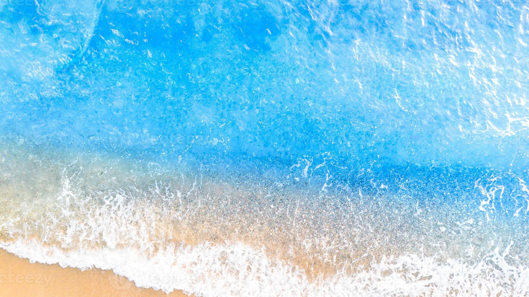 Blue sea wave on sandy beach background. Top view. Copy space photo