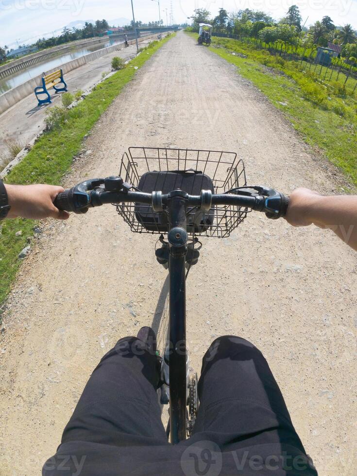 Cyclist riding a bike on the road in the park. POV photo