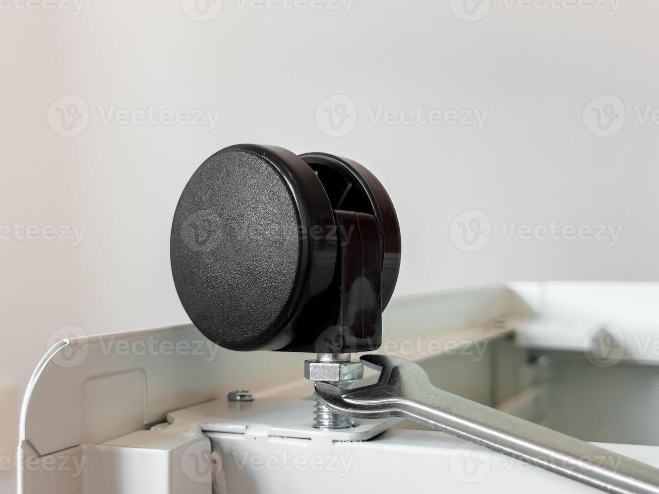 Close up of a black rubber caster wheel on a metal frame with wrench adjustment photo