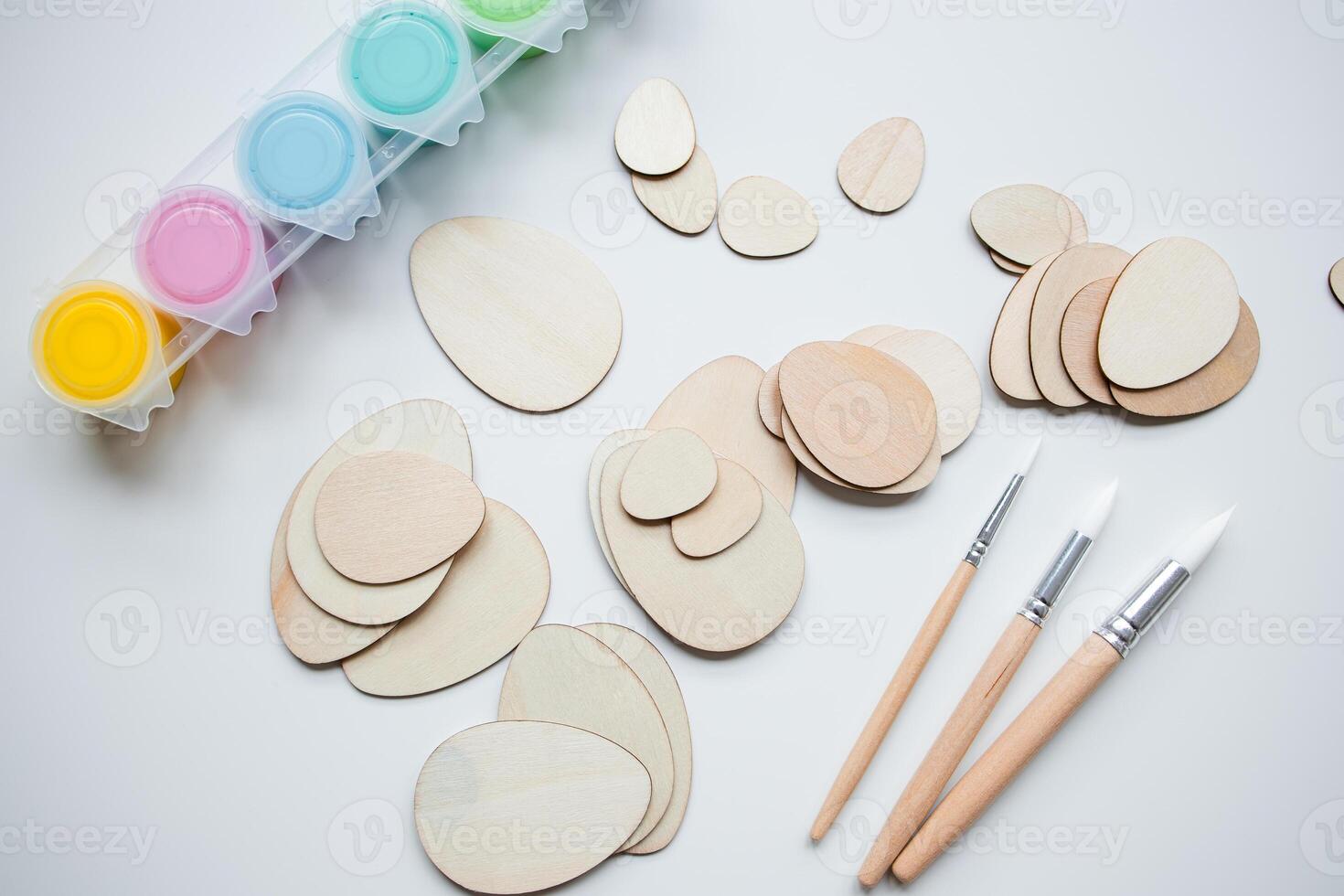 Wooden Easter egg shapes and paints with brushes for DIY crafting projects photo