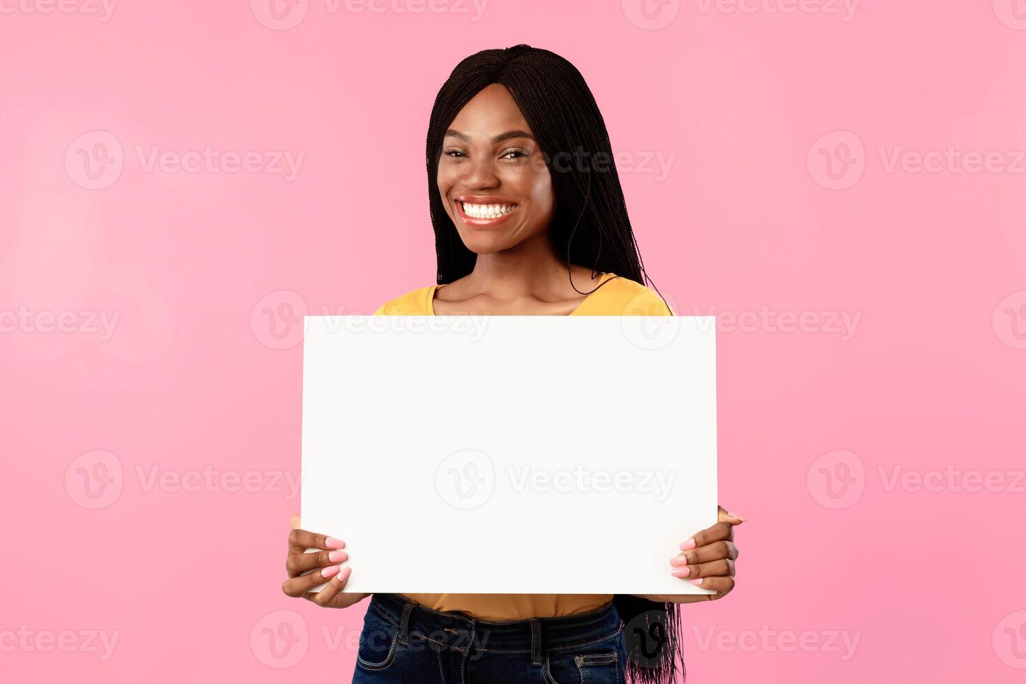 Cheerful Black Woman Showing Empty Paper Poster Advertising Your Text Posing Over Blue Studio Background, Smiling To Camera. Advertisement Banner Concept. Mockup photo