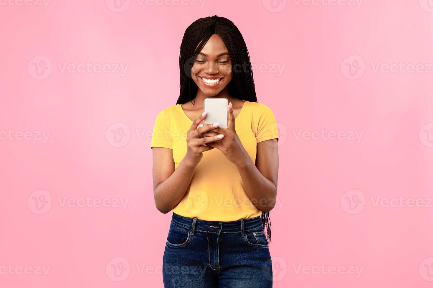 Toothy African American Woman Using Mobile Phone Texting And Browsing Internet Posing Over Blue Background. Studio Shot Of Black Millennial Female Using New Application On Smartphone photo