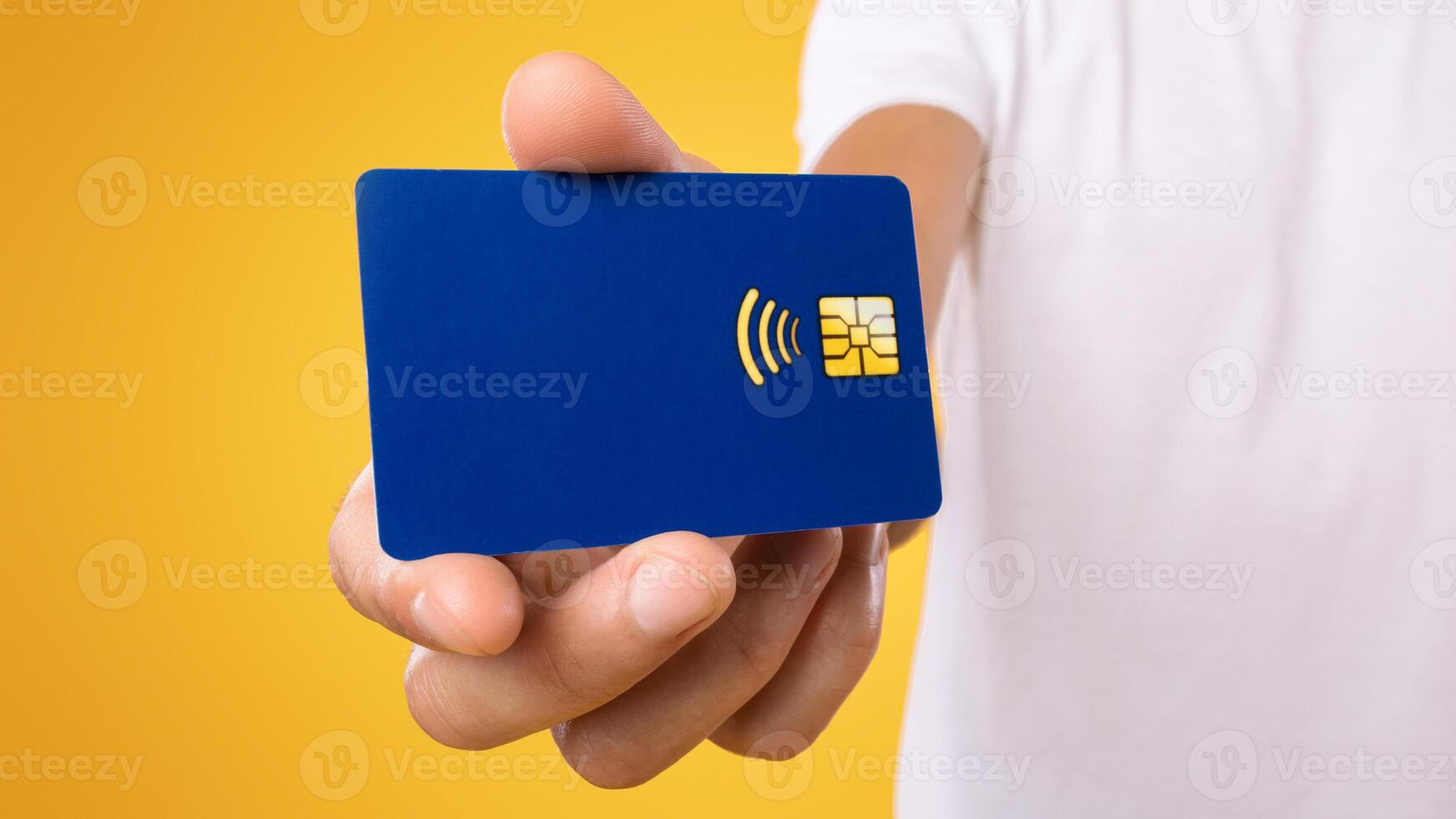 Close up of unrecognizable guy holding personal plastic credit card in hand. Retail, purchase, payment, digital money, banking concept. Banner, panorama, yellow orange studio background photo