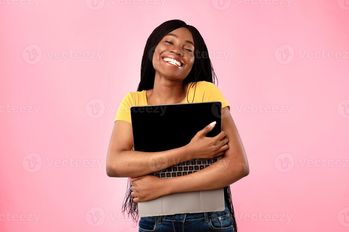 Happy african american female holding and hugging laptop computer posing over blue studio background. I love gadgets. Internet and technologies concept. Freelance and e-learning photo