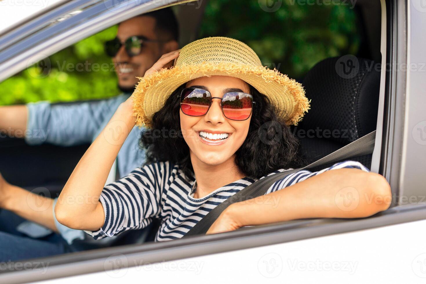 Smiling middle-eastern lovers millennial handsome man and pretty long-haired woman going to beach by car, wearing sunglasses and summer hat, enjoying warm sunny days, closeup shot photo