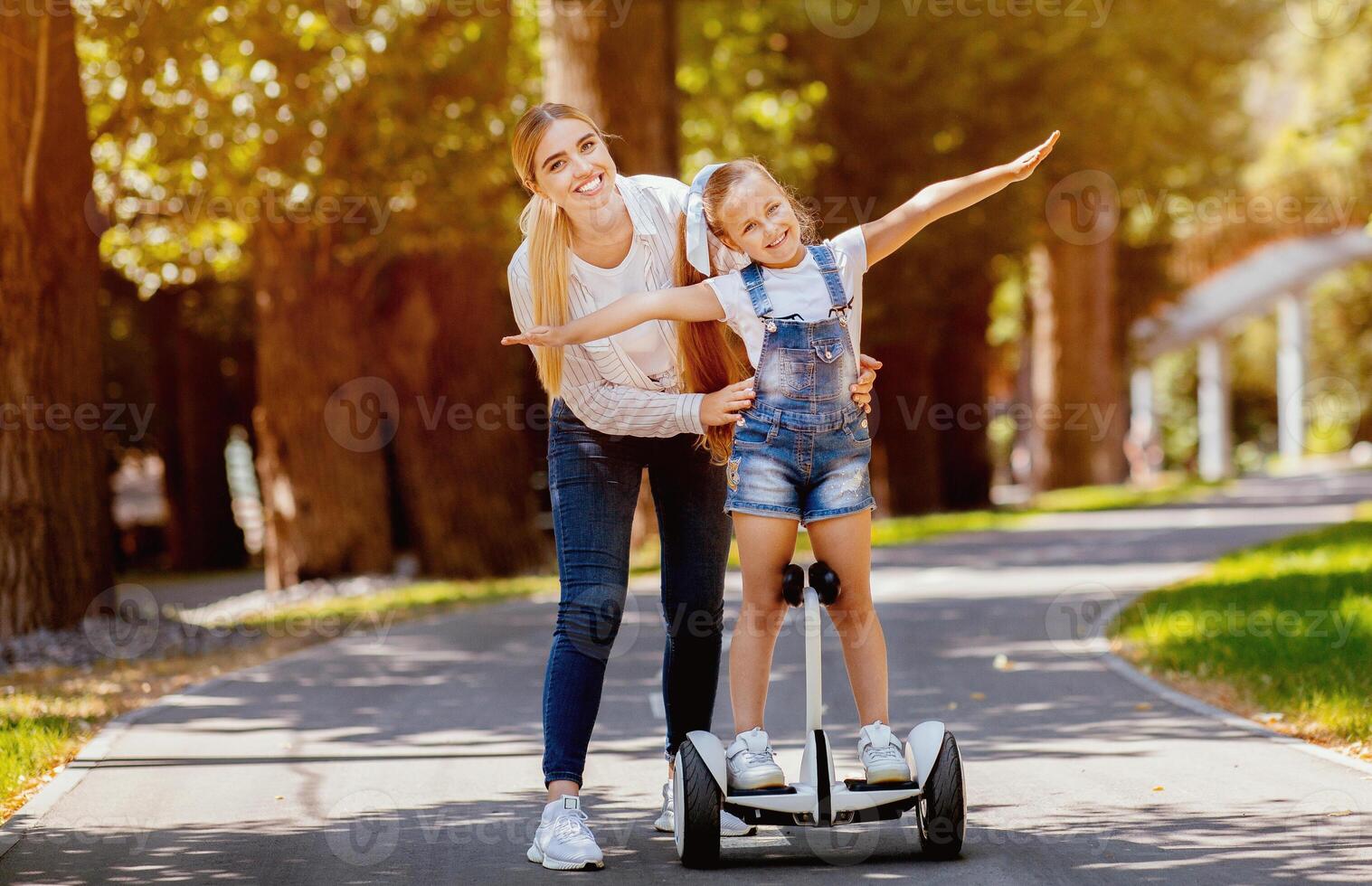 Joyful Mother And Daughter Riding Segway Having Fun In Park Outside. Family Weekend Adventure photo
