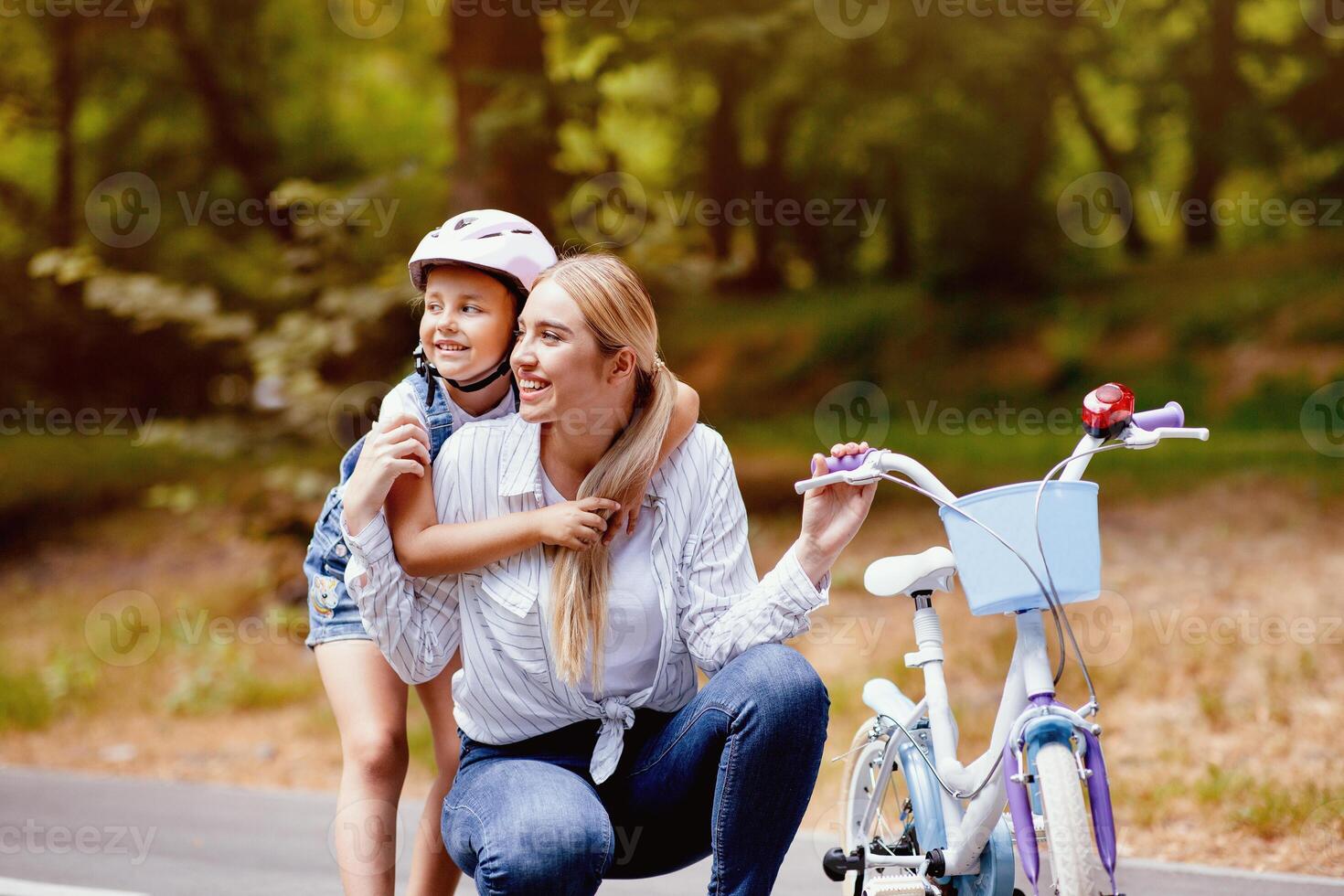 Daughter Hugging Mother Learning To Ride A Bicycle In Park, Wearing Protective Helmet. Family Weekend Adveture Concept photo