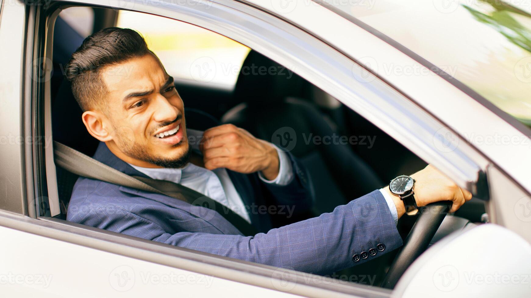 Nervous middle-eastern man in suit going to airport or important business meeting by auto, looking at road and touching his shirt, stuck in traffic, feeling stressed, side view, copy space photo