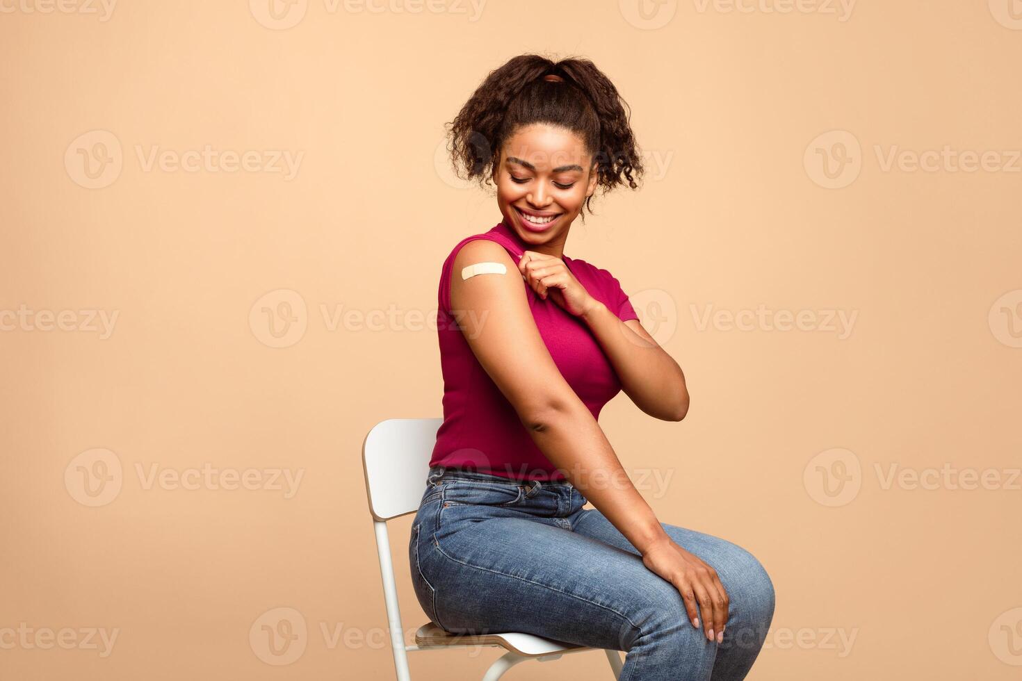 Prevention of flu. African American lady patient showing shoulder with adhesive bandage after anti flu vaccine injection on beige studio background photo