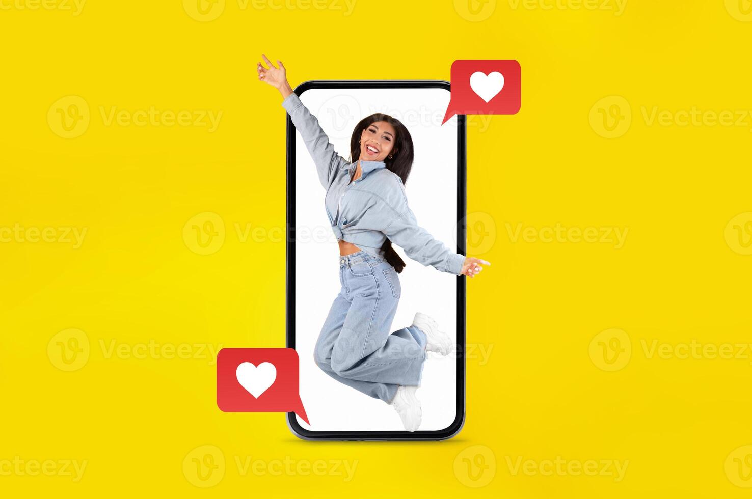 A person is joyfully jumping with excitement, captured within the screen of a smartphone. Heart icons and social media elements enhance the theme of love and connection. photo