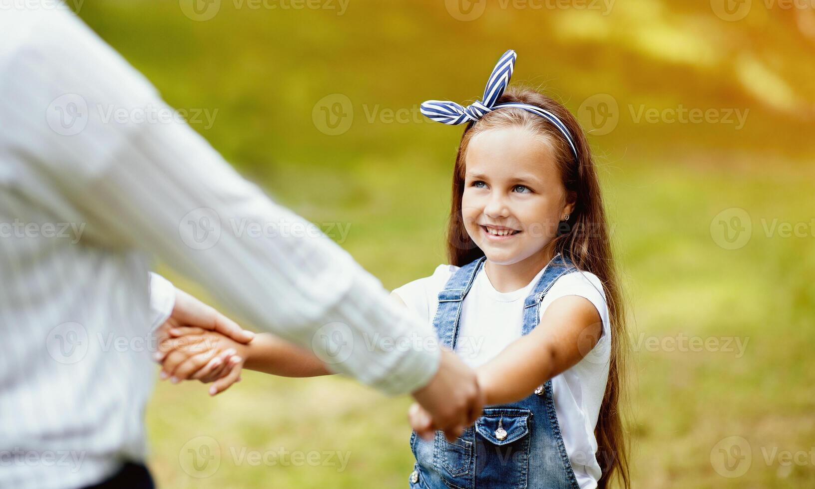Daughter And Mother Holding Hands Spinning Around Having Fun Playing In Park Outside. Family Bonding Concept. Cropped, Selective Focus photo