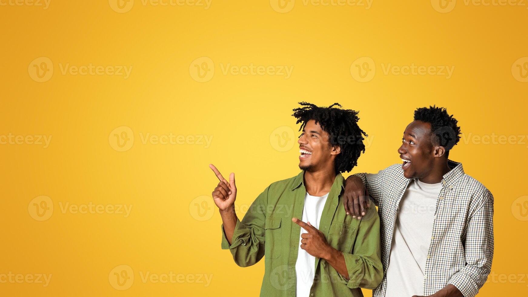 Check This. Two African American Guys Looking And Pointing Aside At Copy Space Over Beige Studio Background, Positive Happy Black Male Friends Demonstrating Empty Place For Advertisement, Panorama photo