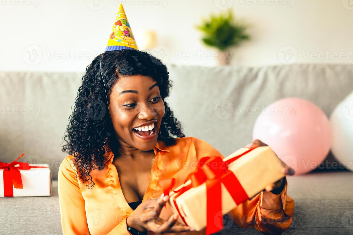 Excited Black Woman Opening Wrapped Birthday Gift Box Celebrating Her B-Day And Receiving Presents At Home. Delivery Service, Holiday Celebration Concept. Front View photo
