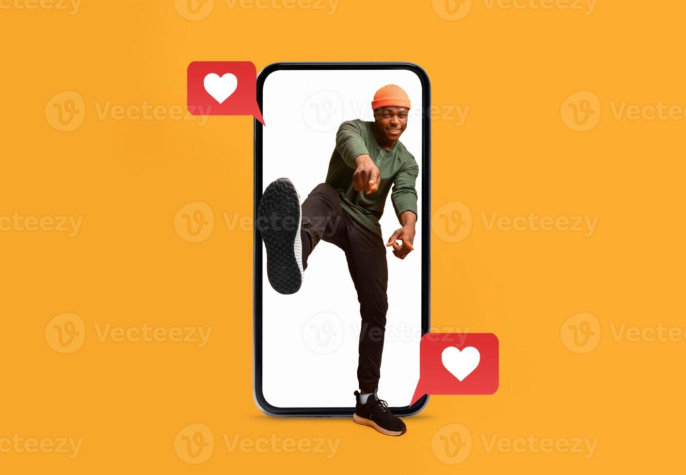 A person playfully poses in front of a bright orange background, emerging from a smartphone. Heart icons indicate active social media engagement, conveying joy and love. photo