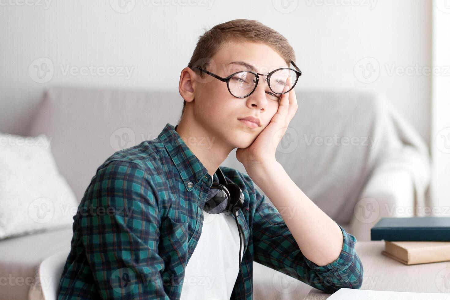 Tired school boy sleeping while doing homework at home, copy space photo
