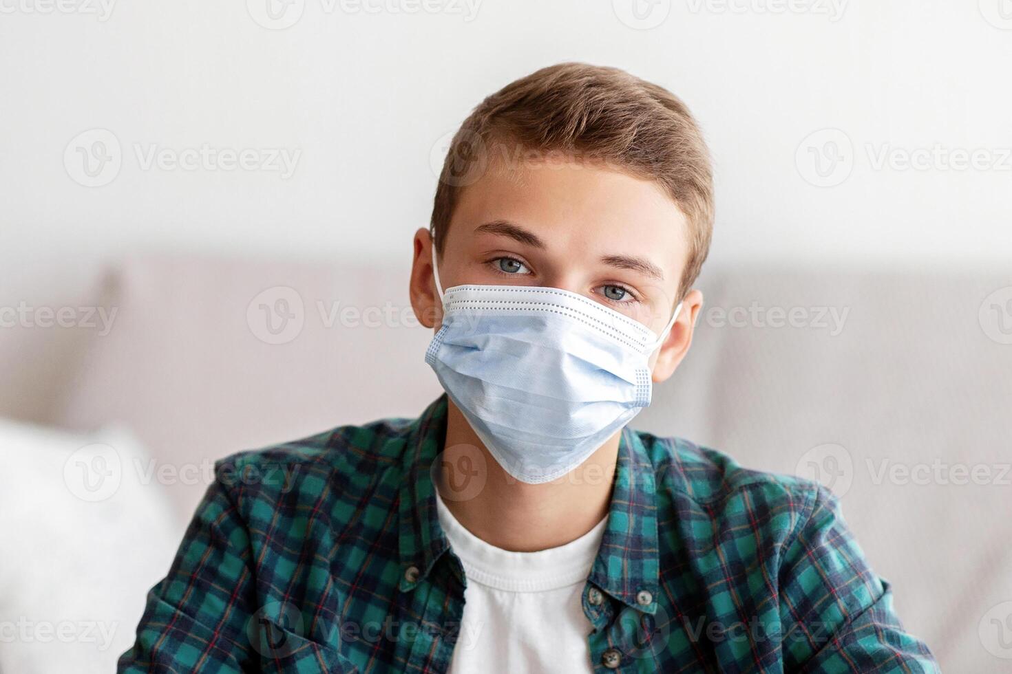 Teenager in protective mask sitting in front of laptop at home, online education during isolation photo