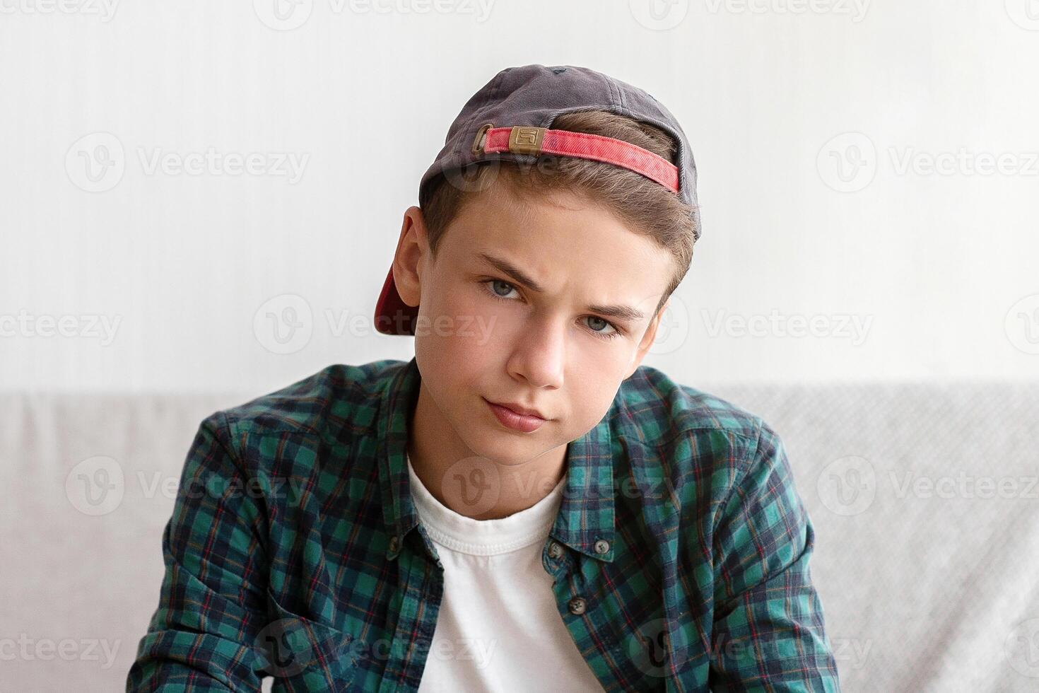 Bored teen boy holding joystick, sitting on couch in his room, eating junk food, copy space photo