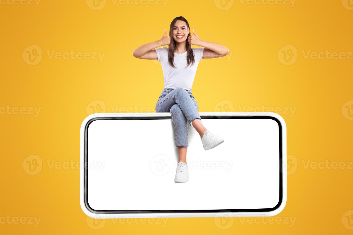 Excited Woman Sitting On Big Smartphone With Blank White Screen And Gesturing Thumb Up Sign, Cheerful Lady Recommending New App Or Website, Isolated On Yellow Background, Mock Up, Creative Collage photo