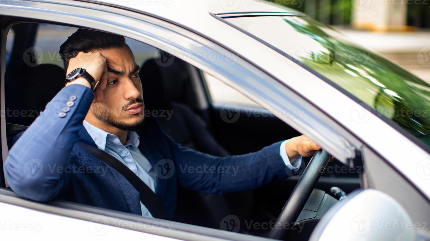 Stressful middle eastern businessman going to airport or important business meeting by car, looking at road and touching his head, stuck in traffic, getting late, side view, copy space photo