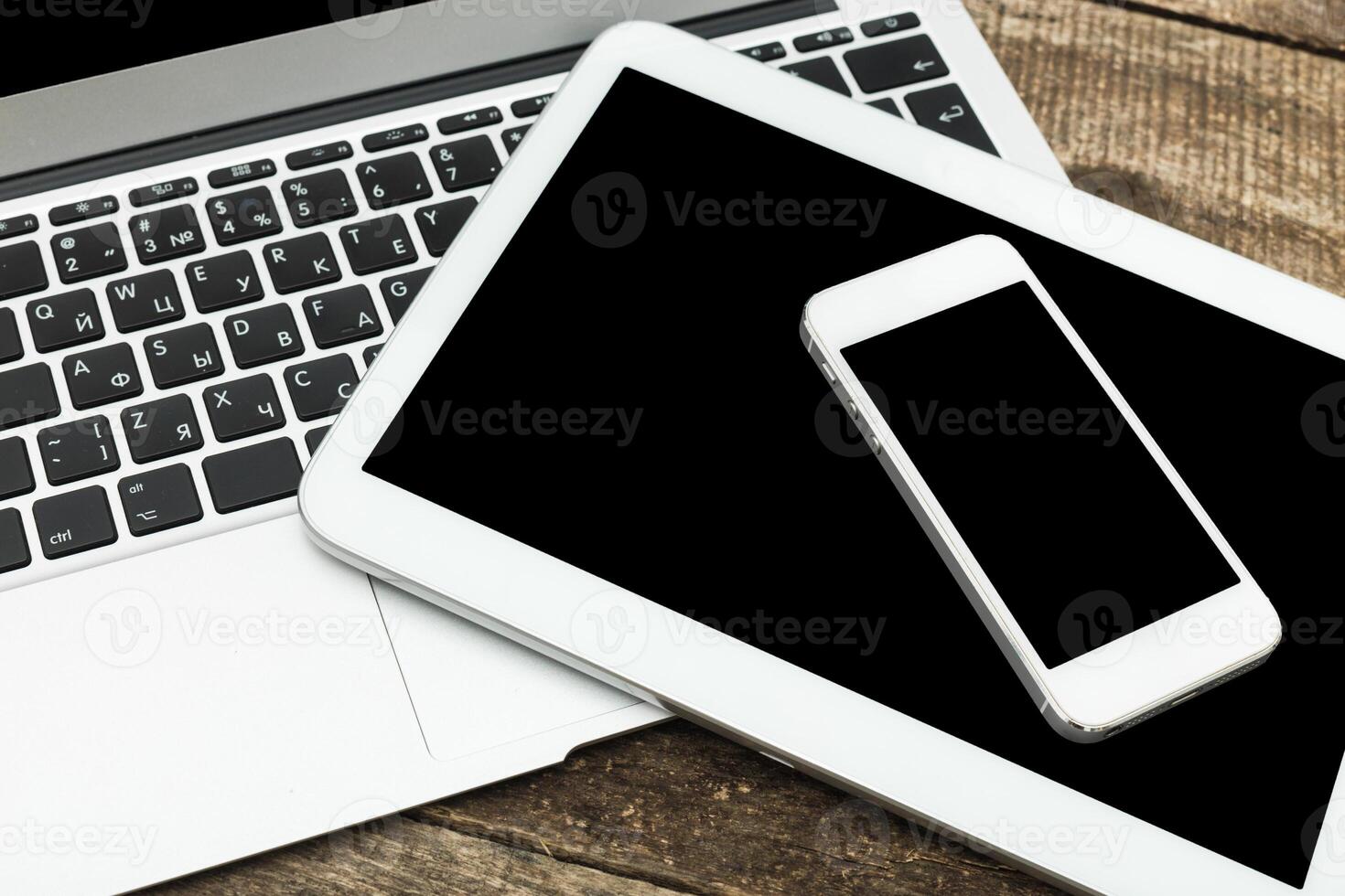 Modern technology setup featuring a laptop, tablet, and smartphone on a wooden surface photo