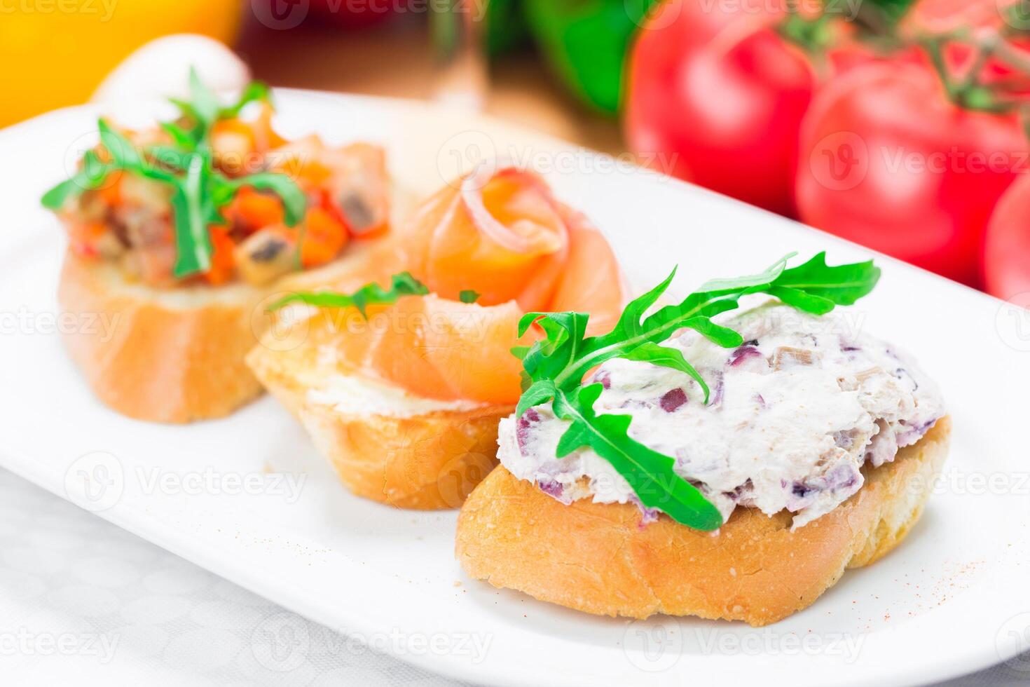 Three colorful tapas served on a white plate in a bright kitchen setting during a casual gathering photo