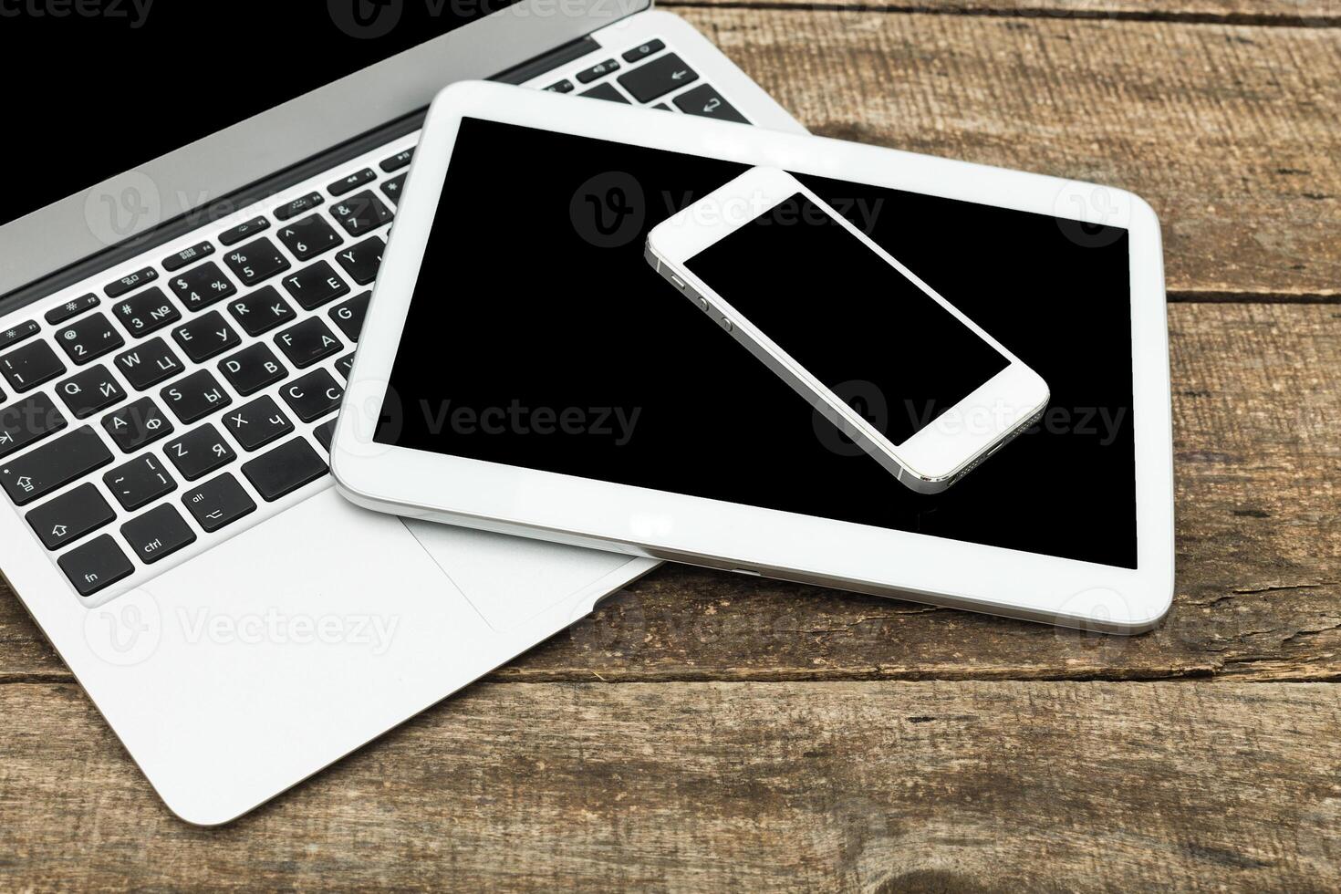 Modern technology setup with laptop, tablet, and smartphone on rustic wooden table for productive work days photo